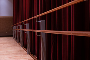 Close-up of a wooden dance bar in front of red stage curtains.